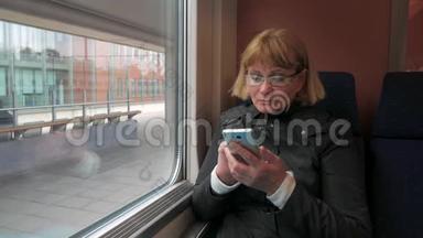 戴眼镜的女人坐在<strong>火车上</strong>，用手指拨电话。